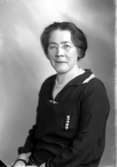 Ateljébild på en kvinna i halsband och glasögon. Enligt Walter Olsons journal är bilden beställd av fru E Franzén.