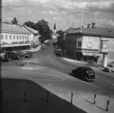 En gatukorsning i centrala Värnamo med butiker längs gatan, längre bort ser man kyrkans torn.