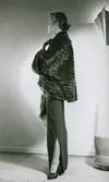 Modell i brun pälsjacka, långkjol med slits och pumps.