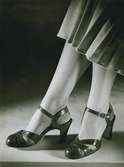 Lädermarknad. Sandaletter, del av plisserad kjol och nylonstrumpor. Wallenberg.