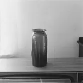Syltburk av brungrönt glas, 25 cm hög. Blåst i samma form som brukets 2-liters buteljer så kallade fuskarbeten.
Tillhör Henning Johannesson
Gävle