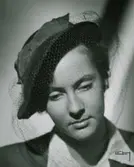 Porträtt av modell i hatt med hattband och flor.