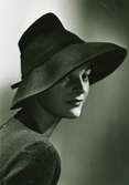 Porträtt av modell i hatt inspirerad av böndernas hattar, japanska träsnitt. Hatt av Jacques Fath för Svensk Damtidning.