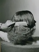 En kvinna kammar sitt hår. Nordiska Kompaniet.