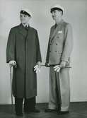 Studentmode 1935. Två unga män i studentmössor och med studentkäppar. Den ene bär en ytterrock med dold knäppning, den andre en ljus, dubbelknäppt kostym. Nordiska Kompaniet. Text med blyerts på baksidan: 