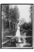 En kvinna på en spång över en bäck i skogen.
Fröken Hulda Johansson, fotograf Sam Lindskogs fästmö.