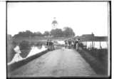 Översvämning den 3 augusti 1910.
Vägen översvämmad, 15 personer vid vägen. Stora Mellösa kyrka i bakgrunden 
Beställningsnr. SM-410.