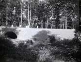 Bild på en nyanläggning av väg och bro. Den är byggd av huggen sten i kallmur. Räcken har inte än kommit på plats. Bron är över Tunaåns utlopp i Tunasjön. Byggd av huggen sten 1932 av AB Vägförbättringar.
