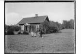 Steninge Slott.
Envånings bostadshus med förstebro.
Familjegrupp tre personer och två hundvalpar framför huset. Skogvaktarbostaden.
Uppland