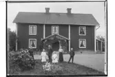 Tvåvånings bostadshus med veranda med snickarglädje.6 personer framför bostaden.Erik Nilsson.