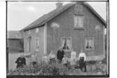 En och en halvplans bostadshus, en flygelbyggnad.8 personer framför huset.Ludvig Andersson.