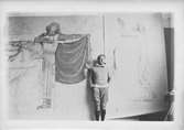 John Bauer vid sidan av sin skiss till väggmåling i al secco i Odd Fellowhuset i Nyköping 1913, 