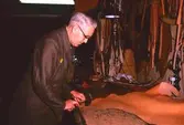 Man som skär ut skinndetaljer ur ett skinstycke.