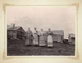 Fyra kvinnor i förkläden på gård