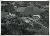 Flygfoto över Hälleberga med kyrkan och en större gård samt åkrar.