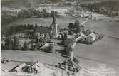 Flygbild över Locknevi kyrkan och bostadshus samt åkrar.