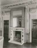 En salong med stuckatur och en öppen spis med en spegel. Bilden är tagen i en bruksherrgård i Överum.