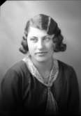 Ateljébild på en kvinna i halsband, klänning och spetskrage. Enligt Walter Olsons journal är bilden beställd av fröken Astrid Håkansson ifrån Lundtorp.