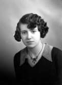 Ateljébild på en kvinna i halsband och klänning. Enligt Walter Olsons journal är bilden beställd av Eva Bengtsson.