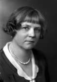 Ateljébild på en kvinna i halsband och klänning. Enligt Walter Olsons journal är bilden beställd av fru H Dahlstedt.