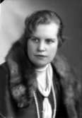 Ateljébild på en kvinna med rävboa, halsband och kappa. Enligt Walter Olsons journal är bilden beställd av fröken Aina Rydén.