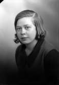 Ateljébild på en kvinna i blus och slipover. Enligt Walter Olsons journal är bilden beställd av Maja Olsson.