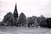 Vy från Frödinge, kyrkan med klockstapeln och stenmuren framför.
