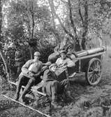 Militärklädda män i en skogsdunge bredvid en kanon. Kamratfest på Kungsbäck