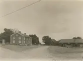 Till vänster: gästgiveribyggningen. Till höger: byggnad inrymmande, från vänster räknat, vagnbod, vedbod, stall och svinhus. Skiftesverk, tegeltak.