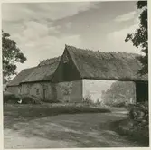 Ekonomibyggnad med stråtak uppförd i sten.