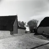 Tvärgata med ladugårdslängor. Döstak med takprydnad.