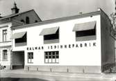 Kalmar Ispinnefabrik. Grundad 1933. Fabrikör Ewald Baumann introducerade glassen i Kalmar. Fabriken låg på Ängö ett slag, i korsningen Gripgatan- Öhnellsgatan. Verksamheten flyttade senare till Strängnäs och ombildades till Hemglass.