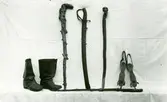 Utställda föremål, ett par läderstövlar, käpp, värja och ett par skridskor.