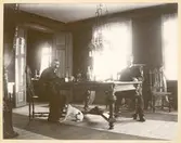 Två män och en hund i en matsal.