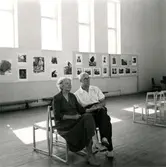 Nilsson, Nils J (1982-1980). Folkskollärare i Uppsala, fotograf och etnolog. Nilsson anlitades av Riksantikvarieämbetet för att dokumentera livet i Kalmar läns skärgård samt livet på Öland. Här sitter han på Kalmar konstmuseum och begrundar en utställning med egna foton.