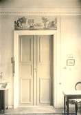 Övervåningen, rum sex. Dörröverstycken, två stycken tryckta mångfärgade på papper, fantasilandskap. Flat grå Kakelugn. Överstycket av Arthur & Robert 1781-1811,