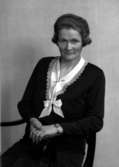 Ateljébild på en kvinna i brosch och rosett. Enligt Walter Olsons journal är bilden beställd av fröken J Bylund.