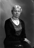 Ateljébild på en kvinna i halsband och hänge. Enligt Walter Olsons journal är bilden beställd av fröken E Engdahl.