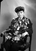 Ateljébild på en man som har tagit realexamen. Han har en mössa och blommor på sig, sittandes på en stol. Enligt Walter Olsons journal är bilden beställd av Ingvar Karlsson.