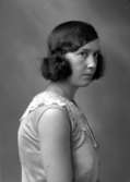 Ateljébild på en kvinna i halsband och klänning. Enligt Walter Olsons journal är bilden beställd av Viola Pettersson.