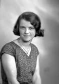 Ateljébild på en kvinna i klänning och halsband med hänge. Enligt Walter Olsons journal är bilden beställd av Ruth Svensson.