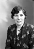 Ateljébild på en kvinna i halsband och klänning. Enligt Walter Olsons journal är bilden beställd av fru T Welander.