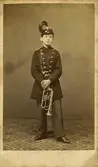 Axel Johansson i en militäruniform med plym. Pojken är en trumpetare.