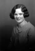 Ateljébild på en kvinna i blus och pärlhalsband. Enligt Walter Olsons journal är bilden beställd av Elisabet Andersson ifrån Kalmar.