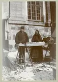 Stortorget mars 1895. Blinde Westergren med hustru. Torgförsäljare utanför Domkyrkan.