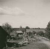 Ekonomibyggnader, gräsgård, staket och vagnar.