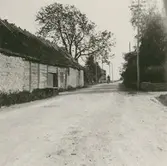 Danjel Pers byggnation. En ekonomibyggnad och en cyklist på en väg.