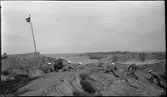 Stridsövning på Stabbo i Stockholms södra skärgård 1929; militärer med handeldvapen ligger på klipphällar och siktar mot  fartygsvrak (skjutmål?) i bakgrunden.