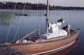Segelbåten Elsi-Anne ligger förtöjd i vid en skärgårdsklippa och ombord pågår arbete med seglet.