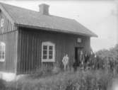 Exteriör. 
Fem herrar framför litet trähus. 
Fotograf: Ellen Kock? Axel Lundbäck m.fl. 
Gullspångssamlingen.
Bilder från Gullspång med omnejd.